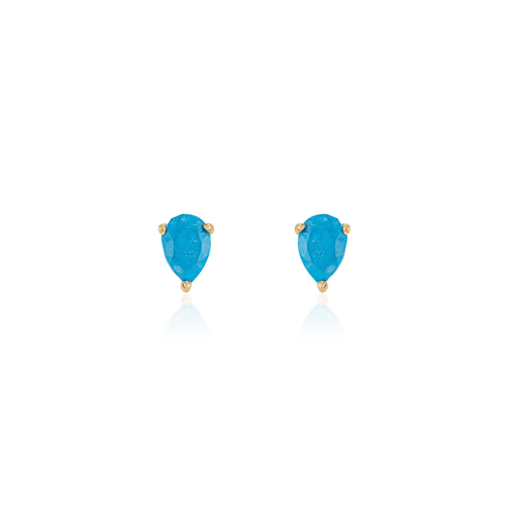 Close-up of elegant turquoise teardrop stud earrings set in 14K gold vermeil displayed on a neutral-toned fabric background. The polished turquoise gemstones are cut in a teardrop faceted shape, reflecting light for a subtle shine—handcrafted minimalist jewelry made in Vermont from Elli Parr.